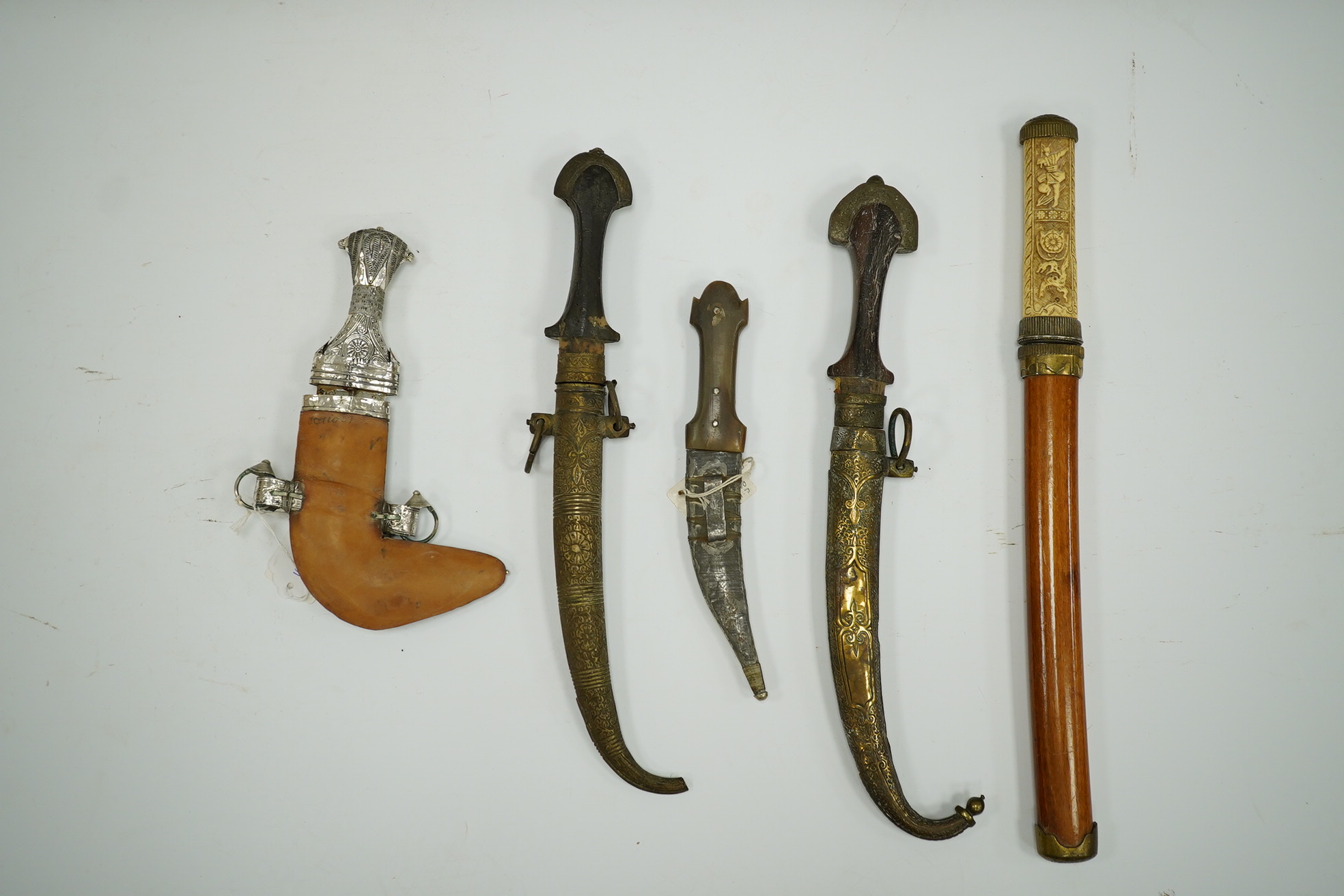 Five daggers; two Moroccan daggers Jambiya, one in brass sheath the other with silver faced brass sheath, both with wooden handles, a small Syrian dagger Shibriya with horn handle, a reproduction Japanese dagger tanto an